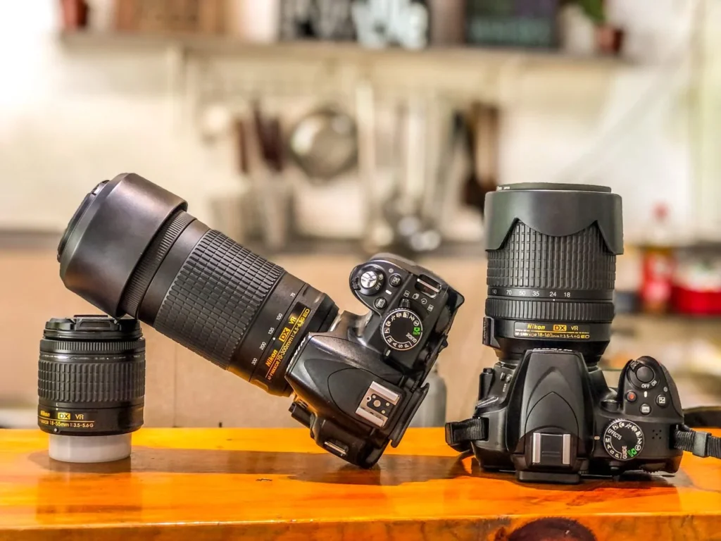 Two DSLR camera bodies with telephoto and prime lenses on a table