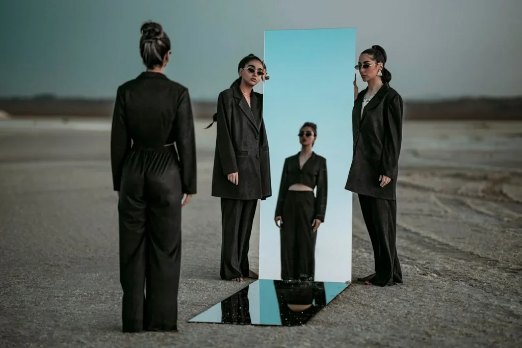 Group of people in black suits reflected in a tall mirror outdoors